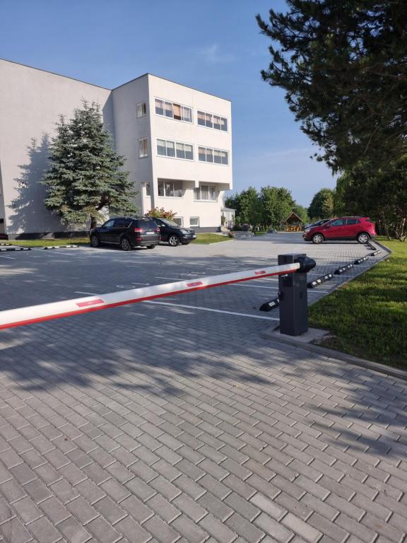 a barrier in a parking lot with cars parked in front of a building at Pas Roma in Šventoji
