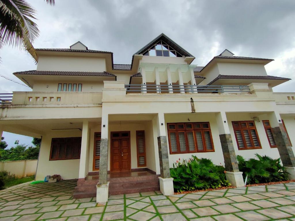 a large white house with a balcony at Nandhanam Holidays in Kannur