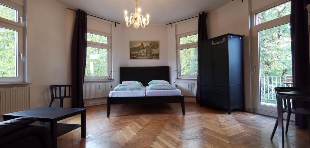 a room with a bed and a table and windows at Central Pension in Duisburg