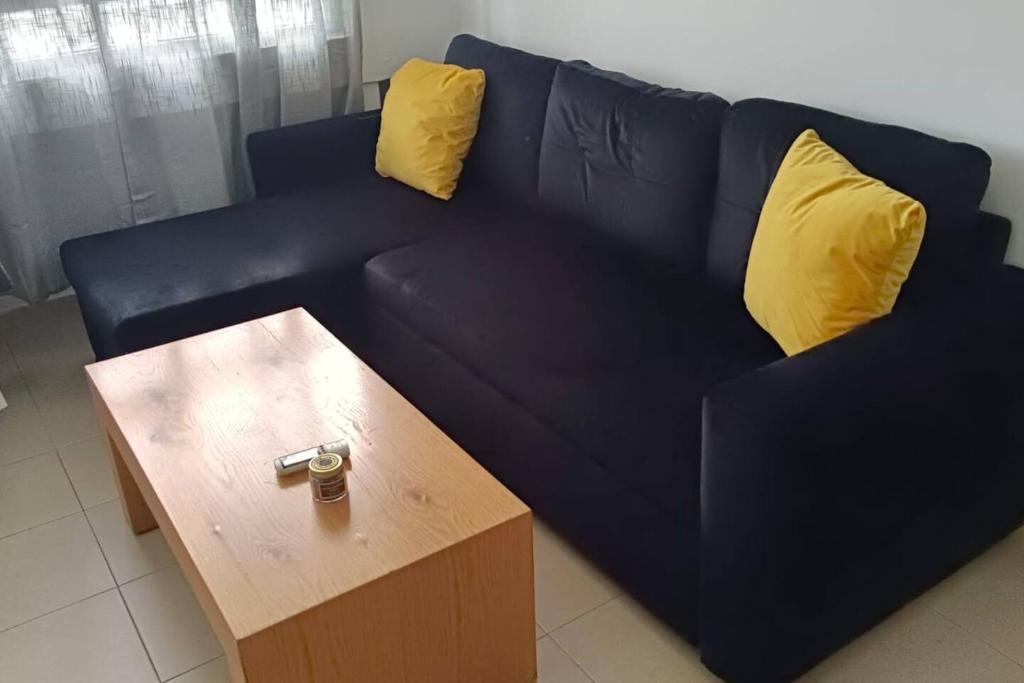 ein blaues Sofa mit zwei gelben Kissen und einem Couchtisch in der Unterkunft 2 rooms close to beach in Tel Aviv