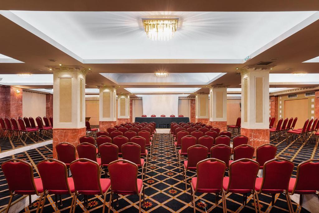 an empty room with red chairs and a stage at Sun Beach Hotel in Agia Triada