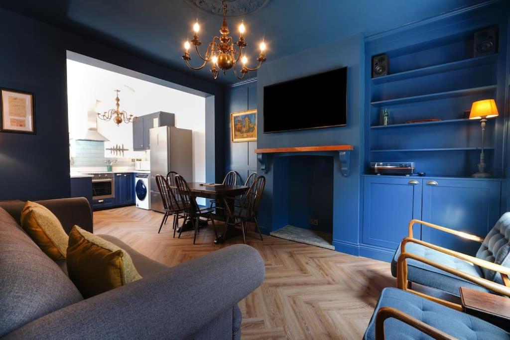 a living room with blue walls and a table with chairs at 4 Bedroom Town House in Macclesfield