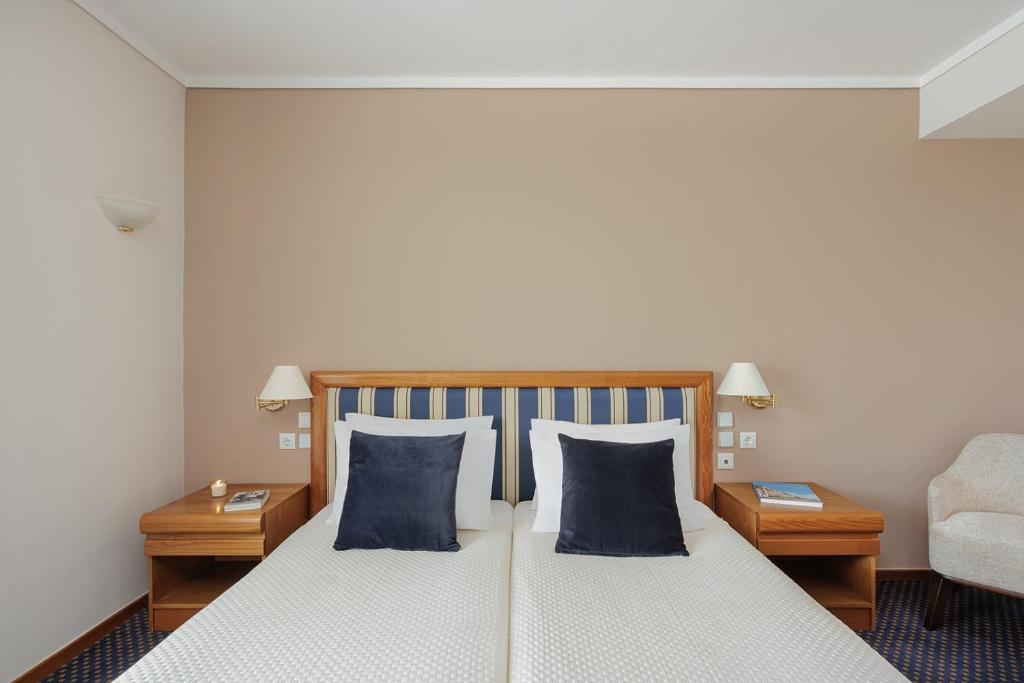 a bedroom with a bed with blue pillows and a chair at Sun Beach Hotel in Agia Triada