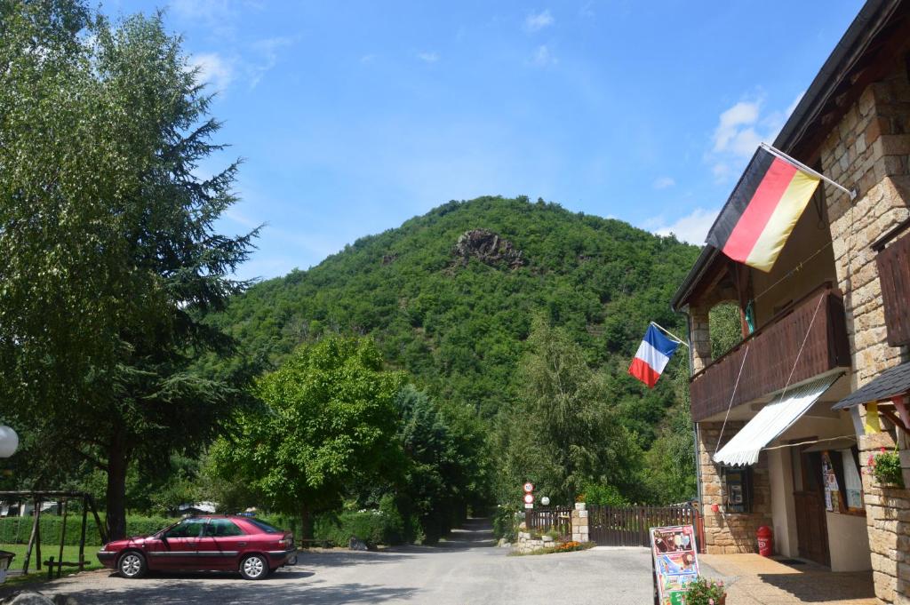 een rode auto geparkeerd voor een gebouw met een berg bij Camping Chon du Tarn in Bédouès