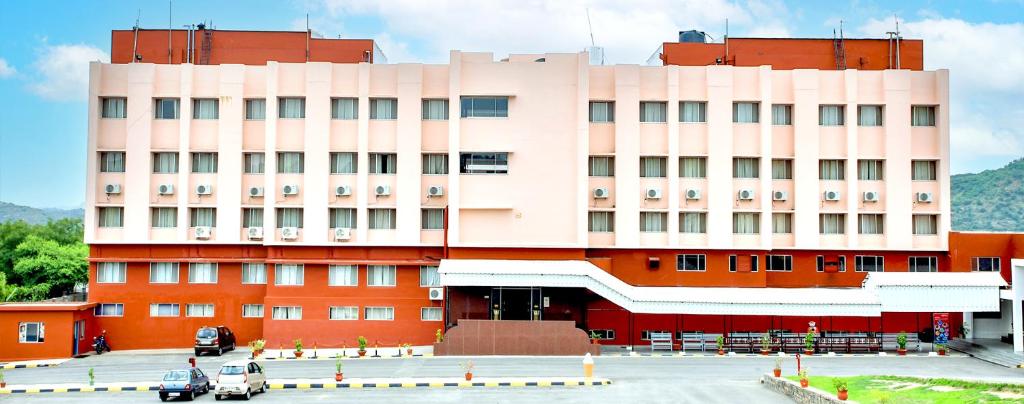 różowy budynek z parkingiem przed nim w obiekcie Ramoji Sahara Shared Accommodation w mieście Pedda Ambarpet