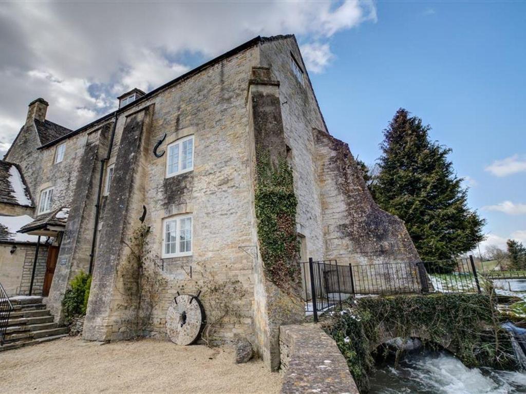 an old stone building with a clock on the side of it at Arlington Mill in Cirencester