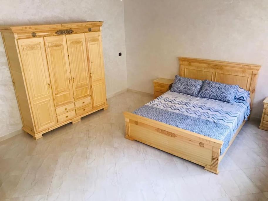 una camera con letto in legno e armadio in legno di Charmant appartement ad Al-Ḥoseyma