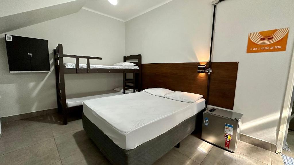 um pequeno quarto com uma cama e um beliche em Suíte nº 03 - Praia das Pitangueiras no Guarujá