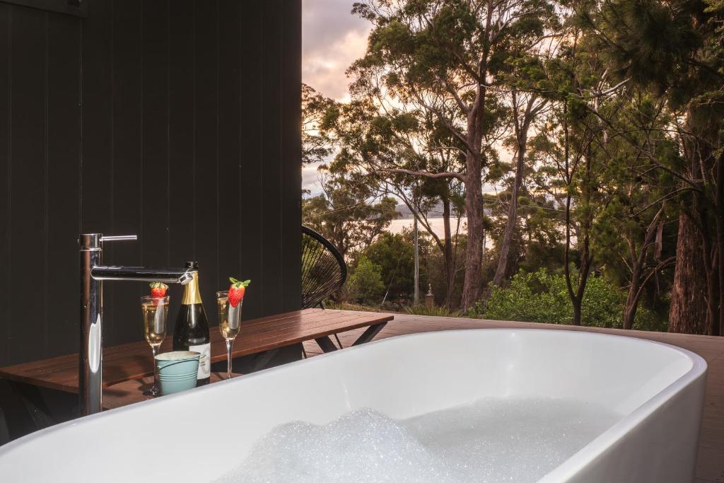 a bath tub in a bathroom with a view of trees at Blyth Retreat, Bruny Island in Simpsons Bay