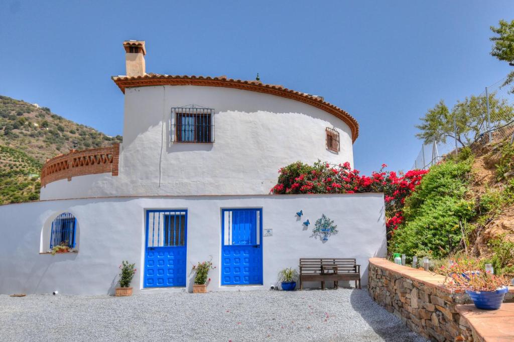 a white house with blue doors and flowers at Casa Redonda in Cómpeta