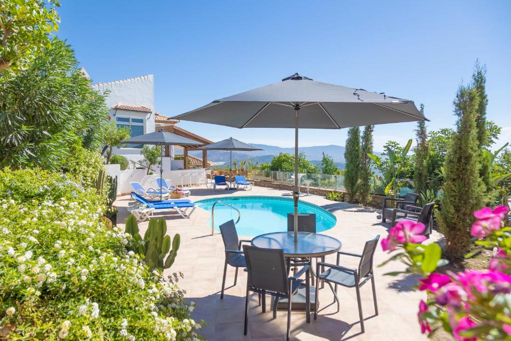 a table with chairs and an umbrella next to a pool at La Nuestra CaRo in Salobreña