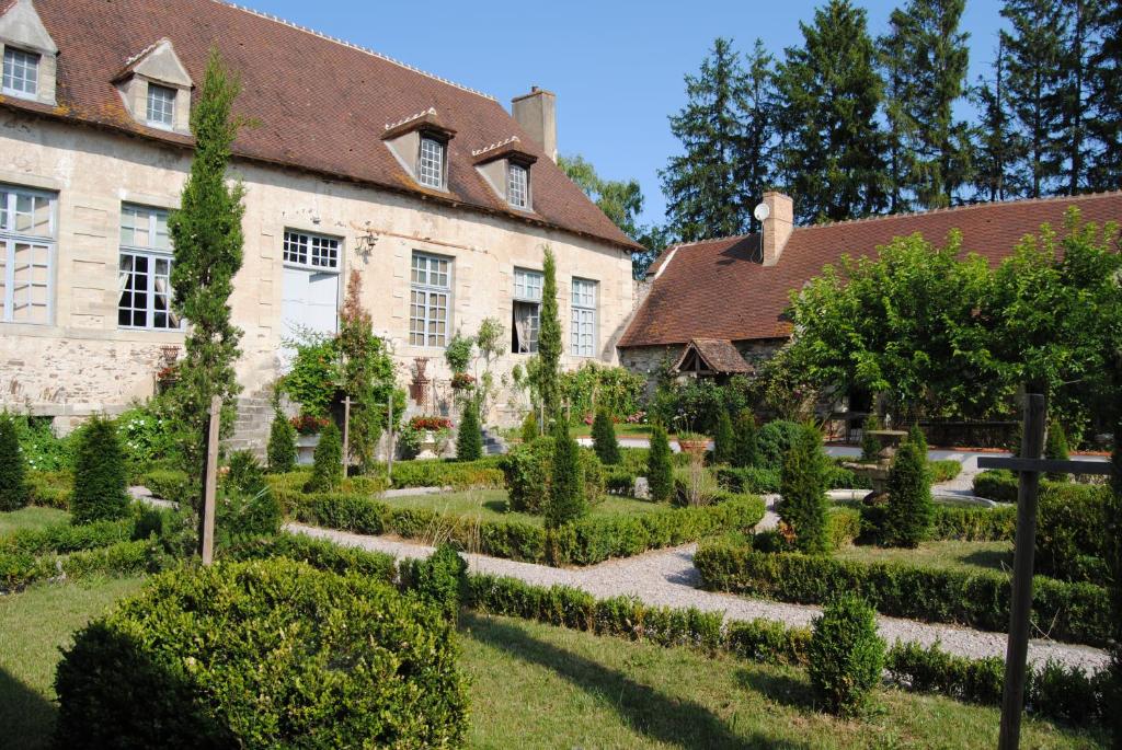 einen Garten vor einem Gebäude mit Bäumen und Sträuchern in der Unterkunft Chateau de Montchoisy 