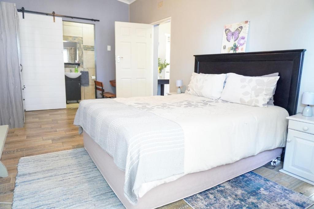 a bedroom with a large bed with white sheets at AVONDBLIJ Apartment in Oudtshoorn