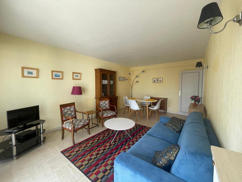 un salon avec un canapé bleu et une table dans l'établissement One Bedroom Apartment Terrasse near the beach, à Cannes