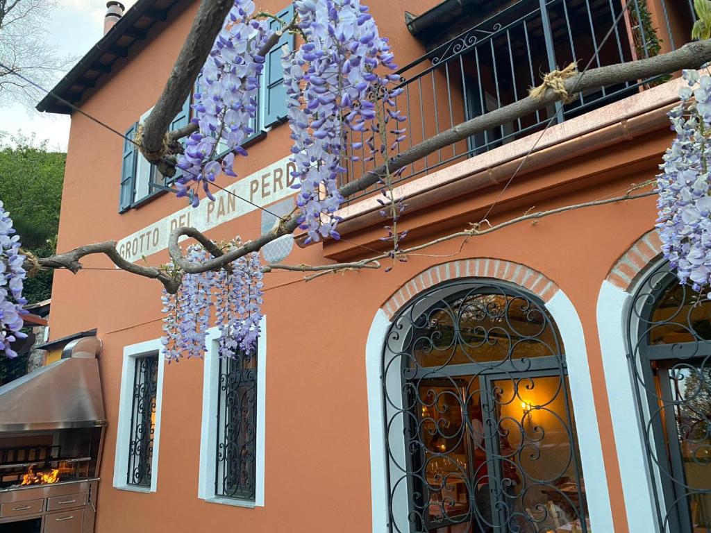 a building with wreaths of purple flowers hanging from it at Grotto del Pan Perdü in Carona