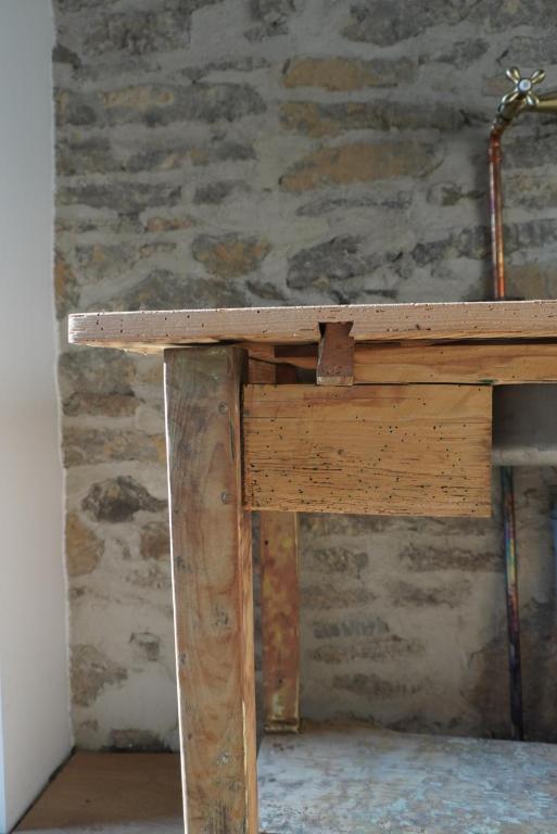 a wooden table in a room with a stone wall at Stodola Počúvadlo in Počúvadlo