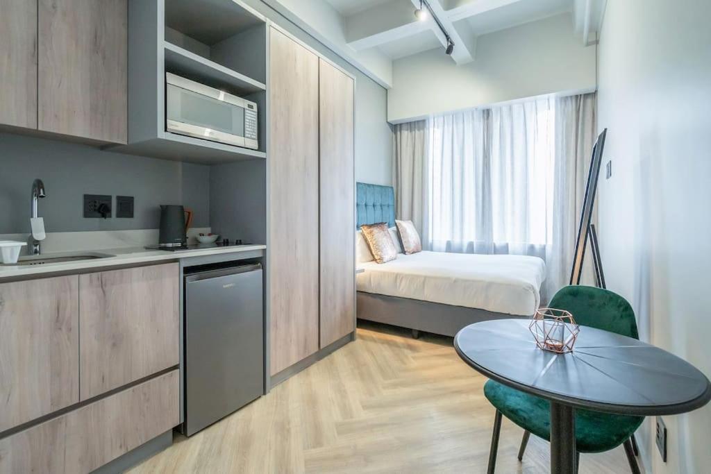 ein Zimmer mit einer Küche und einem Tisch und einem Bett in der Unterkunft City Chic Studio, Cape Town in Kapstadt