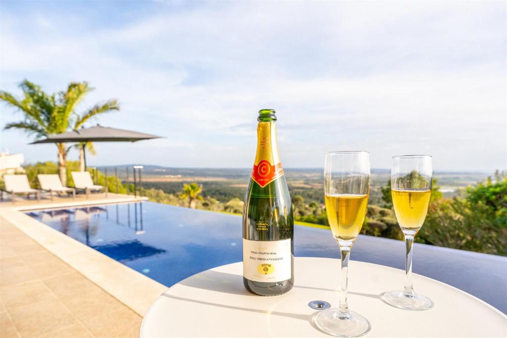 a bottle of wine and two glasses on a table by a pool at Villa bonita con vistas espectaculares, perfecto para familias in Palma de Mallorca