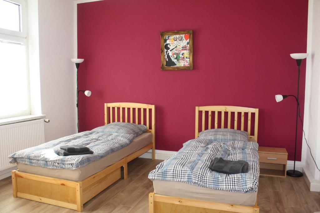 2 Betten in einem Zimmer mit roter Wand in der Unterkunft Betongold in Duisburg