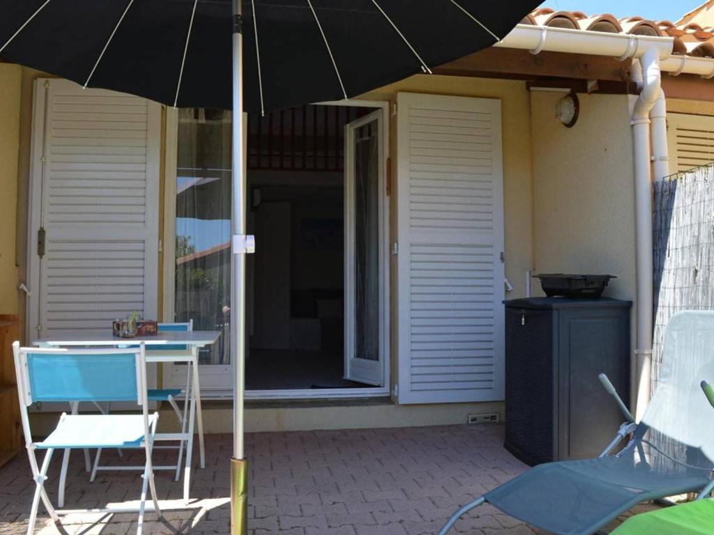 - un parasol sur une terrasse avec une table et des chaises dans l'établissement Charmant Pavillon 4 Pers. avec Terrasse, Piscine, Tennis et Parking à 800m de la Plage - FR-1-229D-271, à Fleury