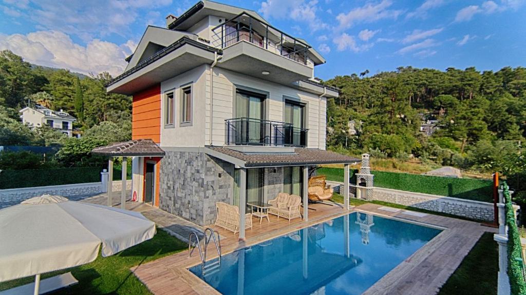 a house with a swimming pool in front of a house at Göcek Villa Can in Belenpınar