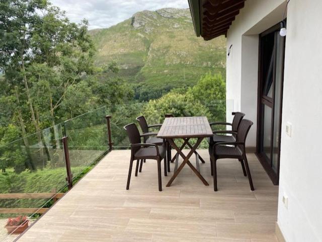 una mesa y sillas en un balcón con vistas en Apartamentos rurales La Teyeruca II en Posada de Llanes