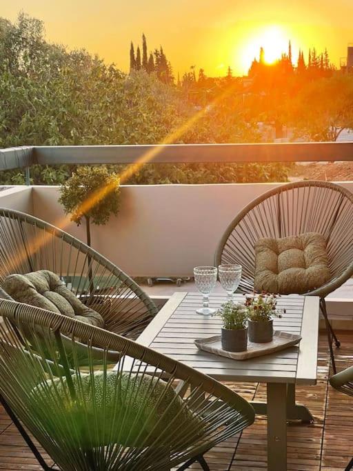 una mesa y sillas en un balcón con vistas a la puesta de sol en Πολυτέλεια και ηρεμία στο κέντρο των Β.Προαστίων.., en Atenas