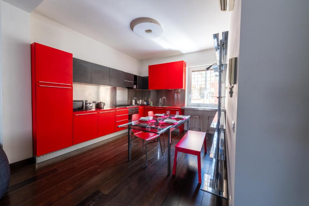 a red kitchen with a table and red cabinets at Casa di Ele in Rome