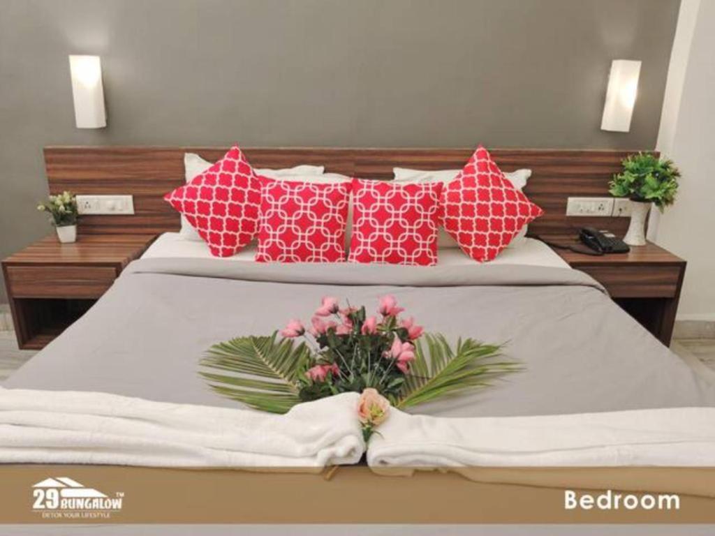 ein Bett mit roten und weißen Kissen und Blumen darauf in der Unterkunft Hilltop suites by 29 bungalow in Khandāla