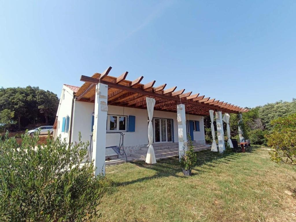ein weißes Haus mit einer Pergola auf einem Hof in der Unterkunft Vacation House Rosa in Supetarska Draga