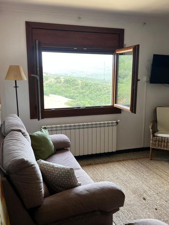 a living room with a couch and a large window at Apartaments La Pertusa 2 in Corçà