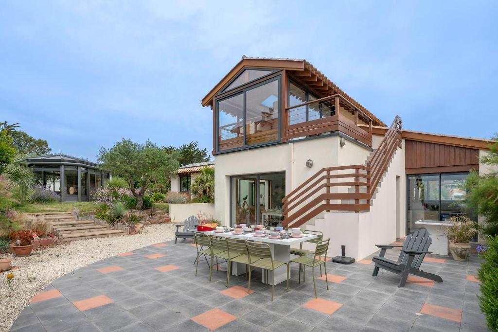 a house with a patio with a table and chairs at Villa Face Mer pour 10 personnes à Préfailles in Préfailles