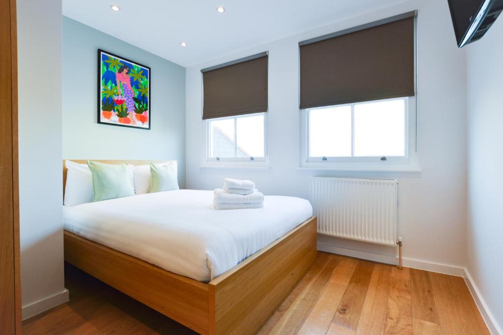 a bedroom with a bed and two windows at Notting Hill Serviced Apartments in London