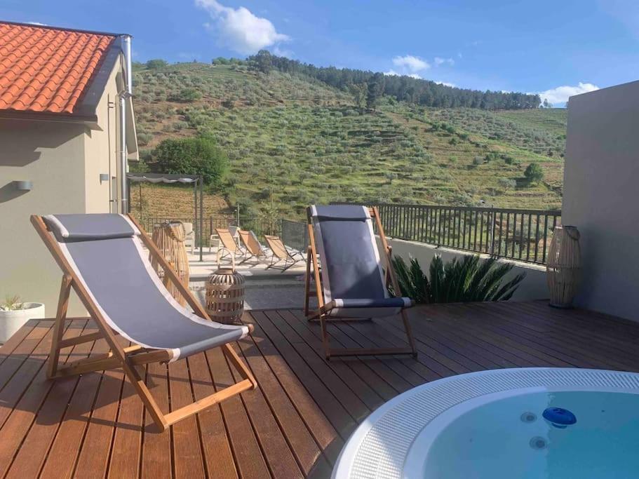 two chairs on a deck with a view of a hill at Cottage Douro Vallée 