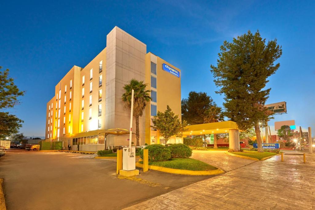 ein Hotelgebäude mit einer Palme davor in der Unterkunft City Express by Marriott Saltillo Norte in Saltillo