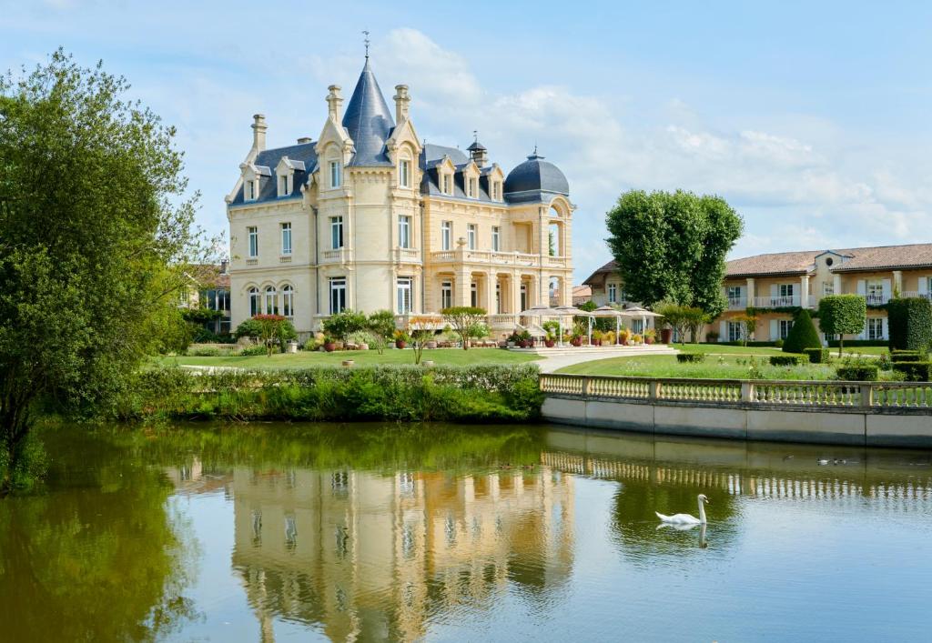 a building with a swan in the water in front at Château Hôtel Grand Barrail in Saint-Émilion