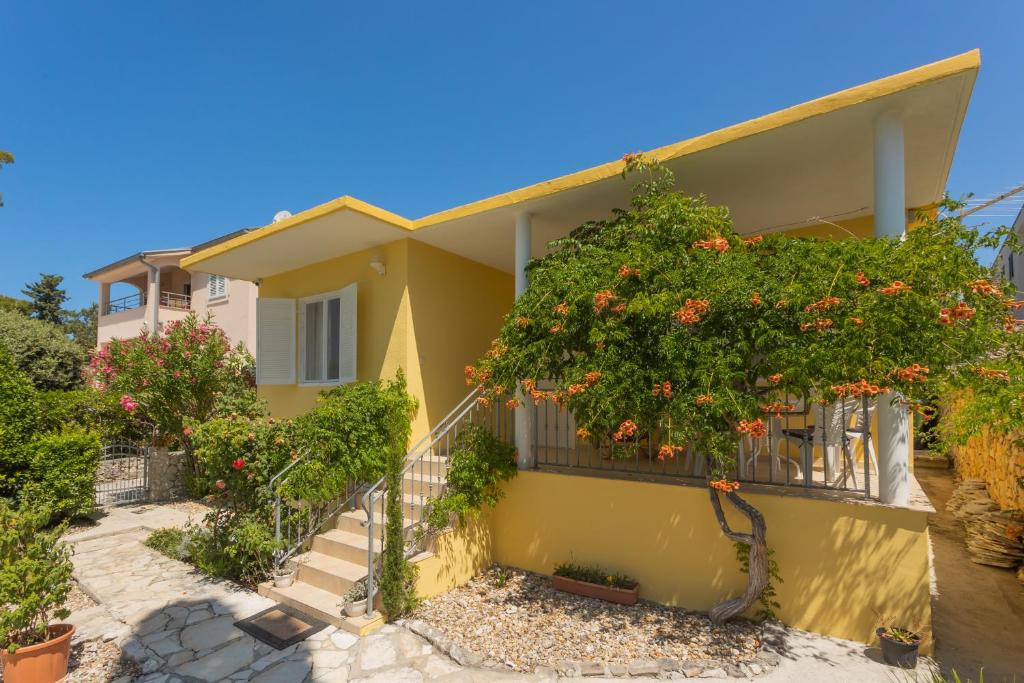 a yellow house with a tree with orange flowers at La Casita Holiday Home in Petrcane