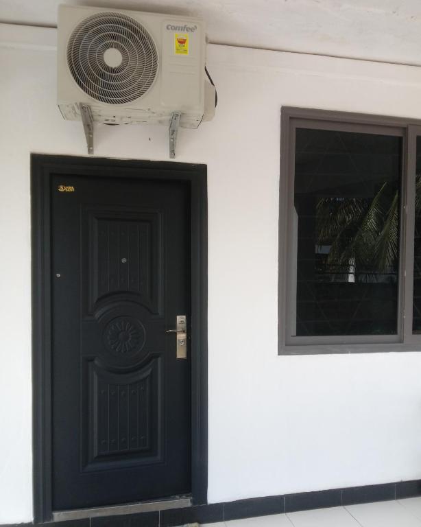 eine Tür mit einem Ventilator neben einem Fenster in der Unterkunft GreenSpring in Cape Coast