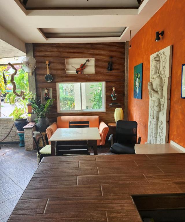 a living room with orange walls and a table and chairs at Bungalows Musch Kamala Phuket in Kamala Beach