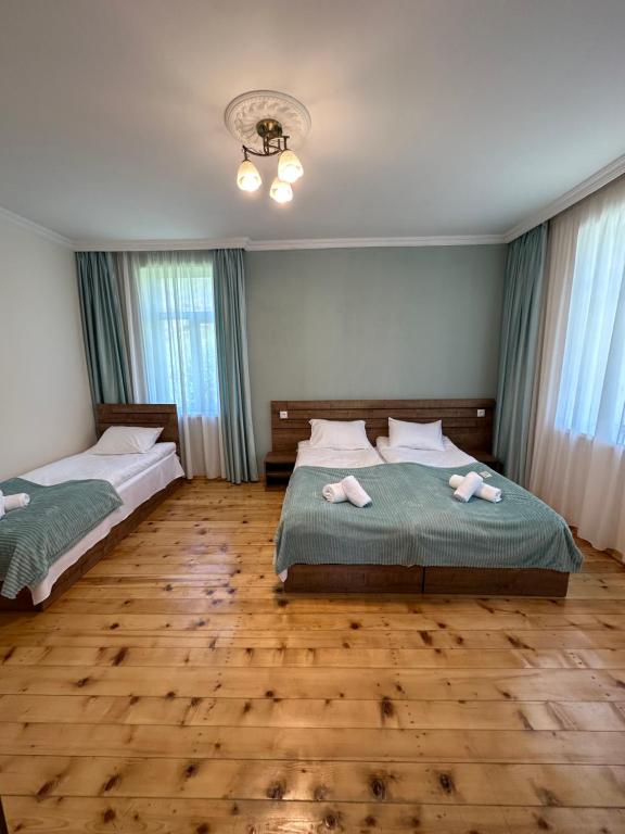 two beds in a room with wooden floors and windows at Polaris Kazbegi in Stepantsminda