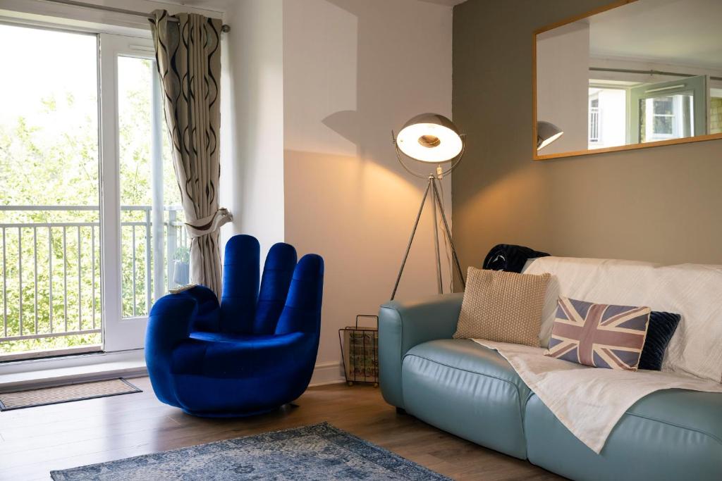 a living room with a blue chair and a couch at Spacious 3 bedroom apartment free parking in Kent