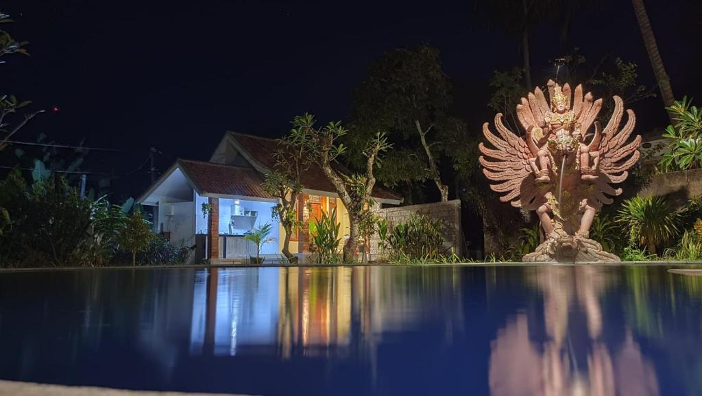 una statua di fronte a una casa di notte di Pranajaya Loka a Tejakula