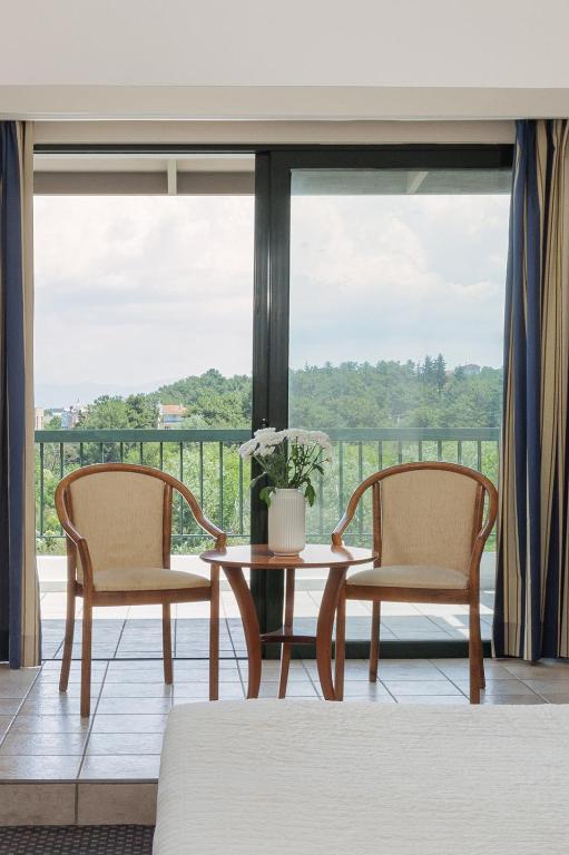 two chairs and a table in front of a window at Sun Beach Hotel in Agia Triada