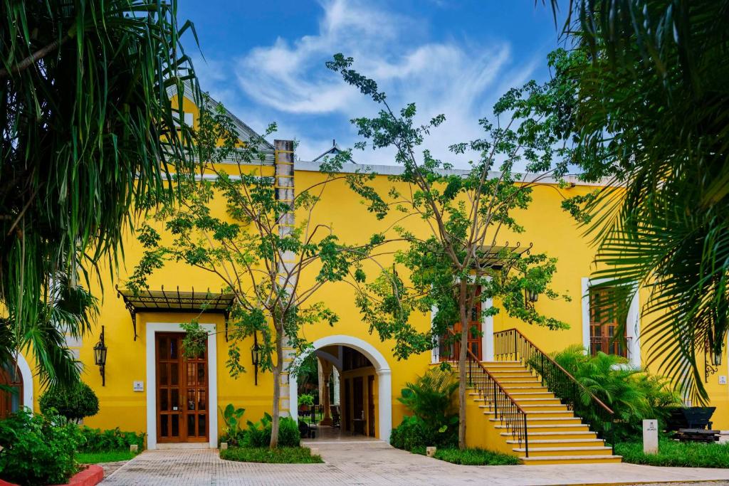 un bâtiment jaune avec des escaliers en face de celui-ci dans l'établissement Hacienda Xcanatun, Angsana Heritage Collection, à Mérida