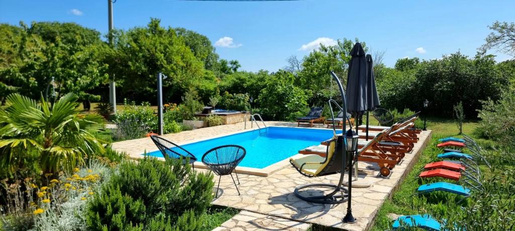a swimming pool in a garden with chairs around it at Villa Stone Medal in Drniš