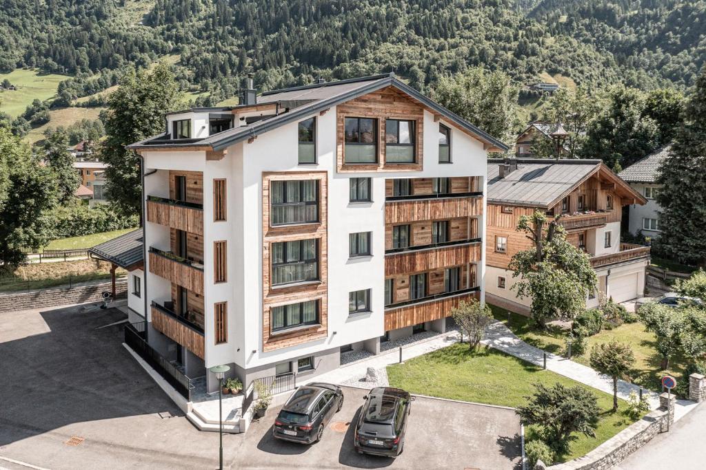 apartamentowiec z samochodami zaparkowanymi na parkingu w obiekcie Apartment NH96 inklusive kostenfreiem Eintritt in die Alpentherme w mieście Bad Hofgastein