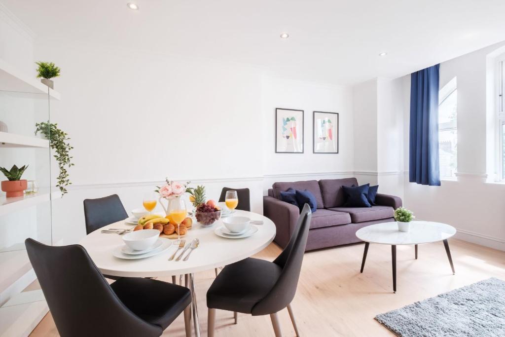 uma sala de estar com uma mesa e cadeiras e um sofá em London Fitzrovia CityApartmentStay em Londres