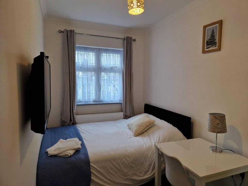 a bedroom with a bed and a table and a window at Captivating 2-Bed Apartment in Ilford in Ilford