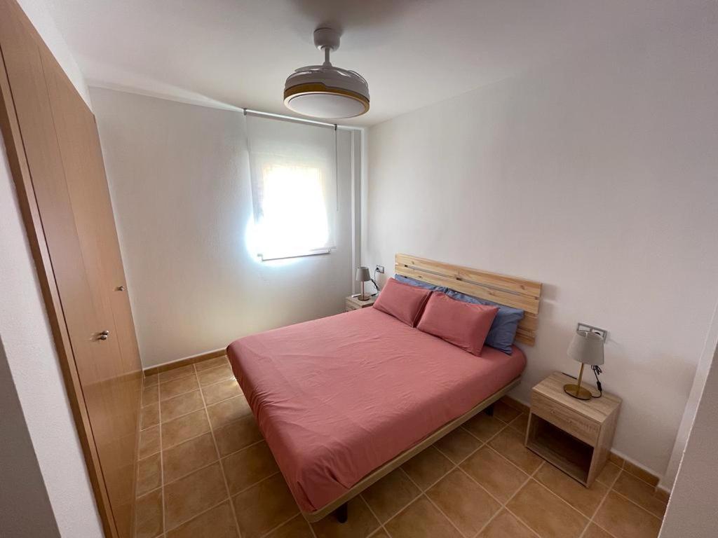 1 dormitorio con cama con sábanas rosas y ventana en LyriosHomes Marina de la Torre Beach, en Mojácar