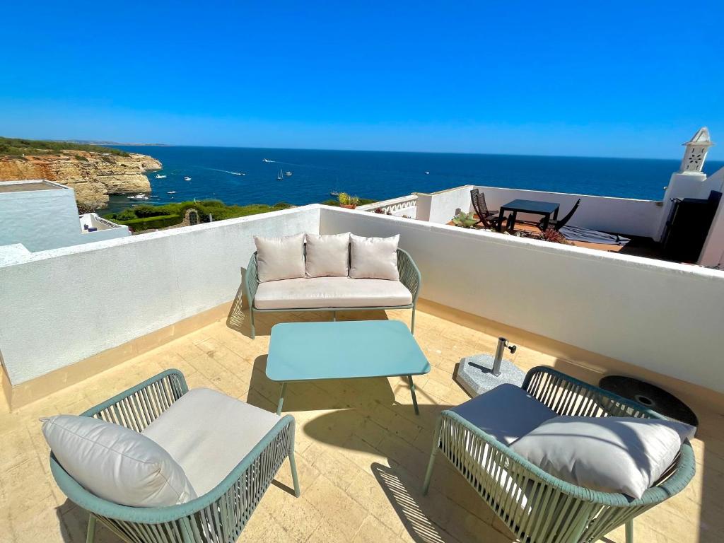 a patio with chairs and a couch and the ocean at Terraços de Benagil By Lemúria in Carvoeiro